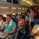 Airplane passengers reading Miami brochures during flight
